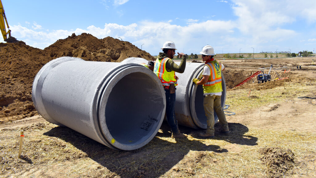 Nelson Pipeline employees with large cement pipes on job site