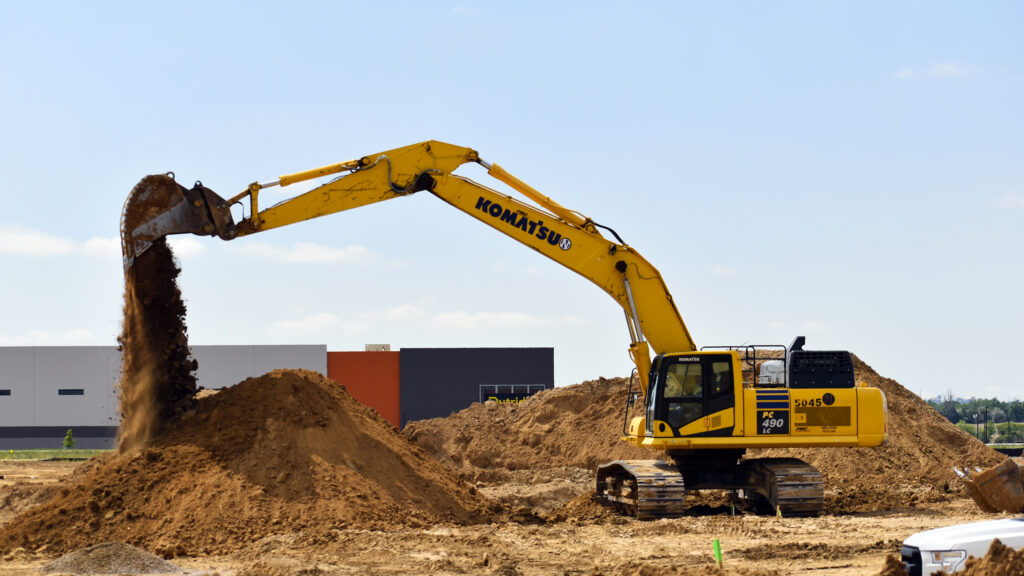 Excavator dumping a bucket load on job site