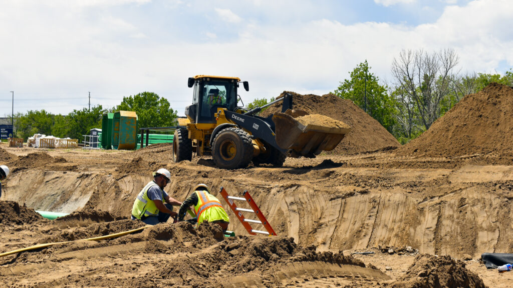Workers and a loader at a ditch on a job site